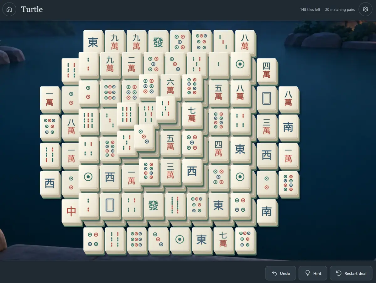 Ivory Mahjong tiles with circle and bamboo symbols in the Turtle layout on a dark playing table.